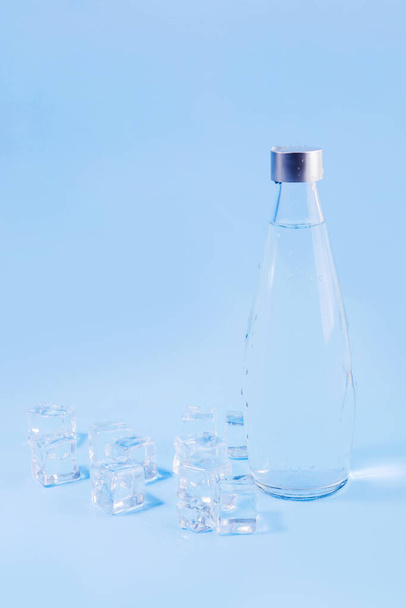 creative summer photo_water bottle and ice, blue background - Foto, Bild