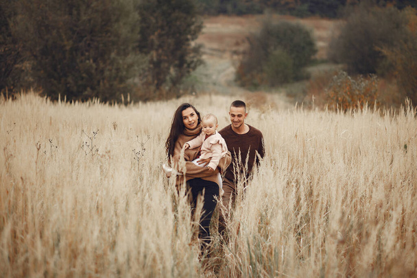 Family with cute little daughter. Father in a brown sweater. Family in a autumn field - Foto, imagen