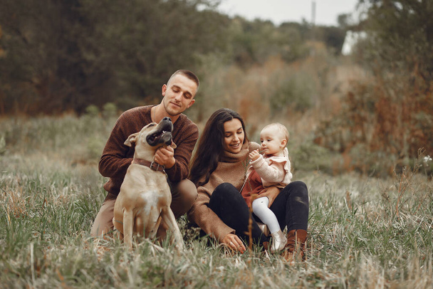 Family with cute little daughter. Father in a brown sweater. Family in a autumn field with dog - Foto, Imagem