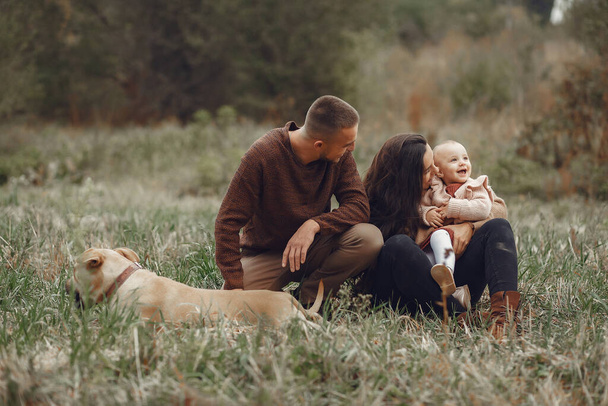 Family with cute little daughter. Father in a brown sweater. Family in a autumn field with dog - Foto, afbeelding