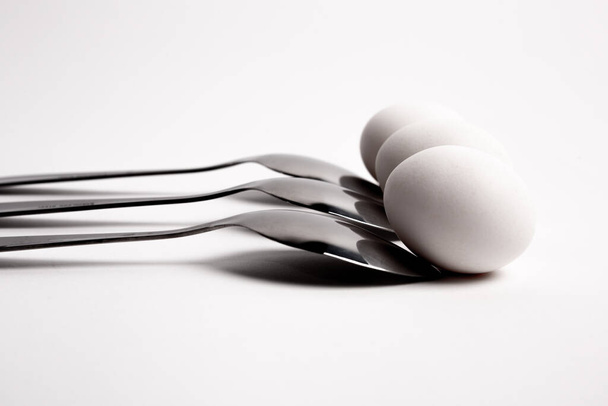 Chicken egg on metal forks, spoons isolated on white background close-up.An egg that is set on top of two forks, spoons. Eggs have so many uses from diet to baking recipes. - Fotó, kép