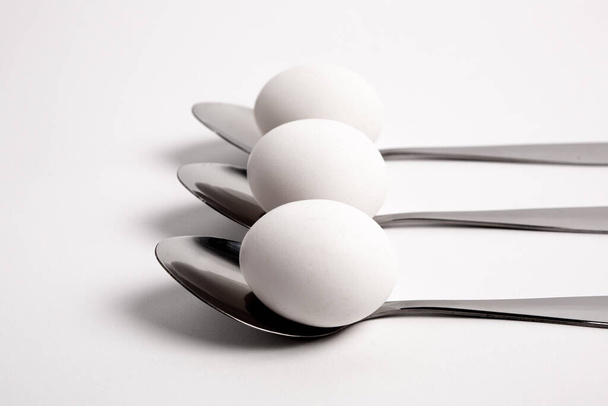 Chicken egg on metal forks, spoons isolated on white background close-up.An egg that is set on top of two forks, spoons. Eggs have so many uses from diet to baking recipes. - Photo, Image