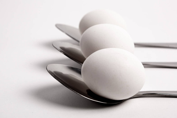 Chicken egg on metal forks, spoons isolated on white background close-up.An egg that is set on top of two forks, spoons. Eggs have so many uses from diet to baking recipes. - Fotoğraf, Görsel