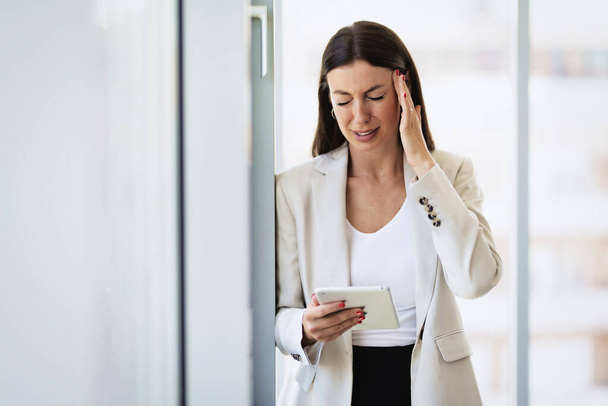 Cropped shot of an attractive businesswoman standing alone in her office and suffering from a headache. - Fotografie, Obrázek