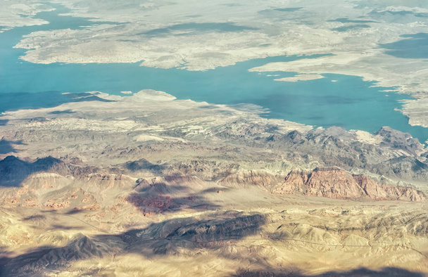 An aerial view shows a beautiful mountain landscape that rises from the desert surrounding Las Vegas, Nevada with landforms and Lake Mead - Φωτογραφία, εικόνα