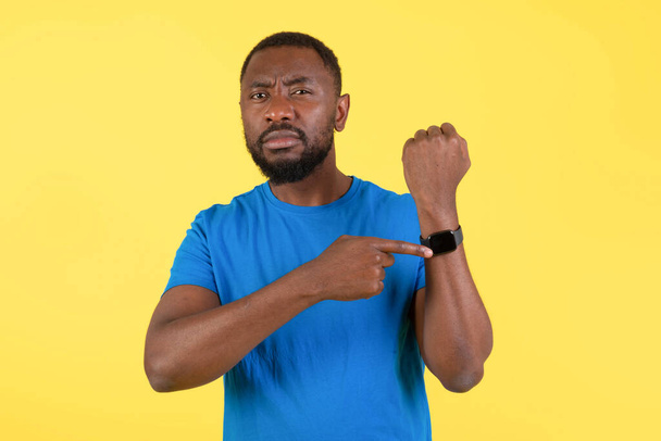 Deadline. Discontented African American Man Showing Smartwatch On Wrist Looking At Camera Over Yellow Background In Studio. Guy Having Problem With Time Management - Foto, afbeelding