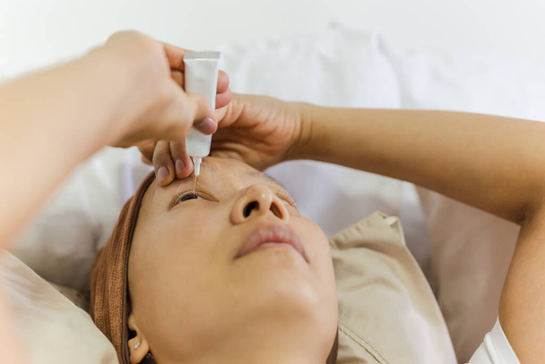 Asian woman uses eye drops for eye treatment - Photo, image