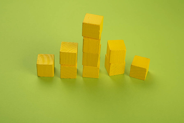 Yellow wooden chips in the form of a tower on a light green background - Foto, imagen