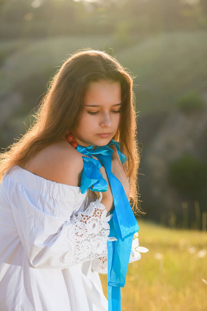 A teenage girl with a gymnastic ribbon on a hillside. Girl on the background of bayrak. Soft back light. - Zdjęcie, obraz