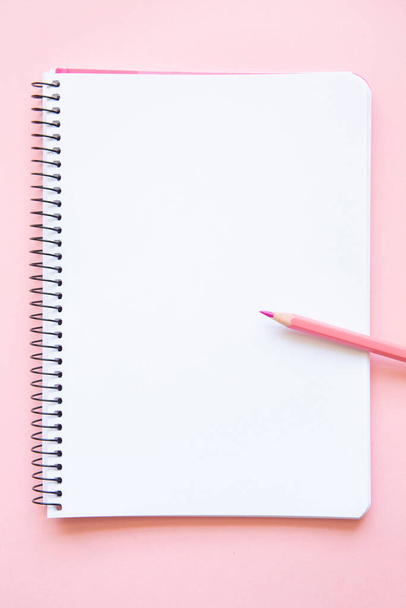 pink pencil on notepad with blank page on pink background - Foto, afbeelding