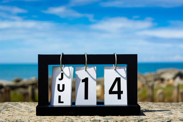 Jul 14 calendar date text on wooden frame with blurred background of ocean. Calendar date concept. - Фото, изображение
