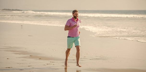朝のワークアウト。健康な男が海岸を走ってる。精力的な夏だ。ランナーは自由を感じる。朝を楽しんで。持久力とスタミナ。スポーツ選手は海で勝つために速く走る. - 写真・画像