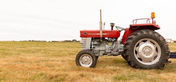 Panoramic view of a tractor standing in a crop field. The day is cloudy. Concept of agriculture and rural life. Space for text. - Valokuva, kuva