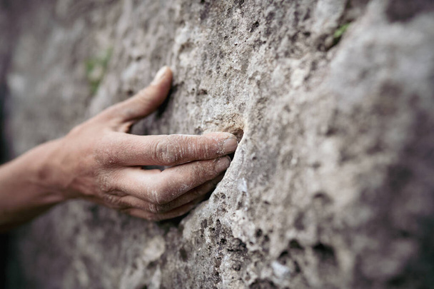 Plan rapproché d'un homme adulte tenant une main sur un rocher, illustration pour l'escalade. - Photo, image