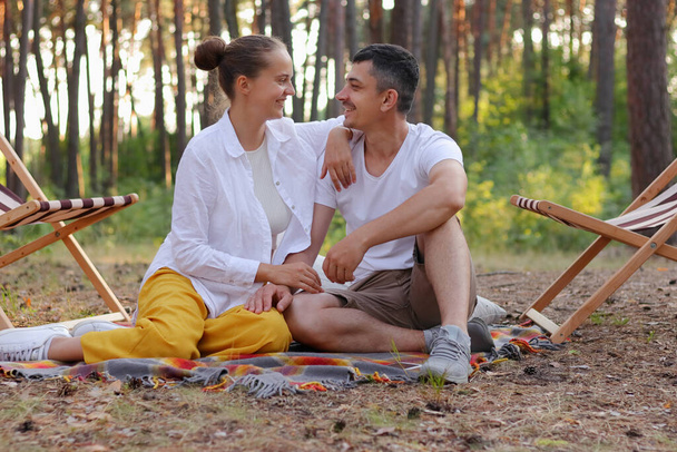 Photo of good looking pleased couple enjoying time together, looking at each other with love and hugging, expressing romantic feelings, beautiful nature. - Фото, зображення