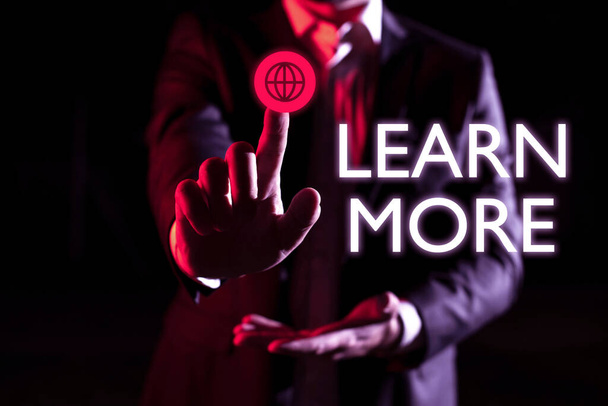 Text sign showing Learn More, Word Written on Deepen knowledge of the thing you want to do or new skill Businessman Pointing Important Infortmations With One Finger. - 写真・画像