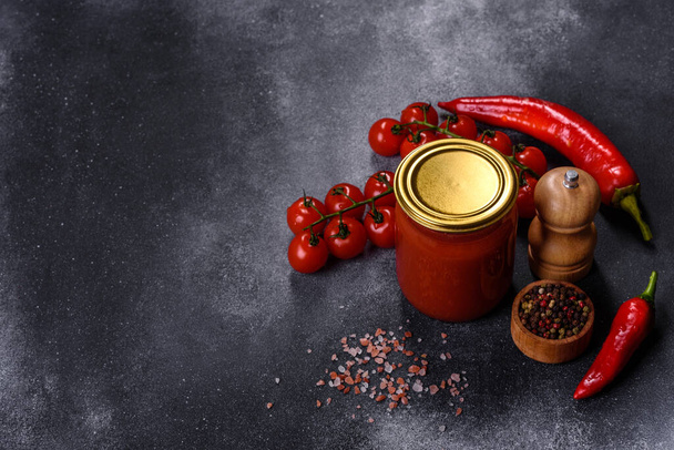 Пряний солодкий томатний соус з часником, перцем і травами в скляних банках. Консервовані помідори в томатному соку
 - Фото, зображення