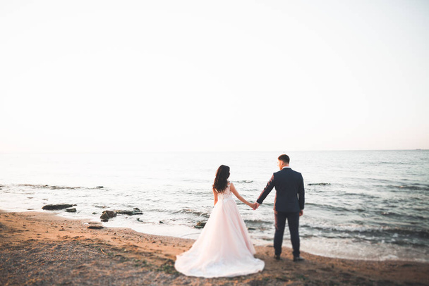 Happy and romantic scene of just married young wedding couple posing on beautiful beach. - Foto, Imagen
