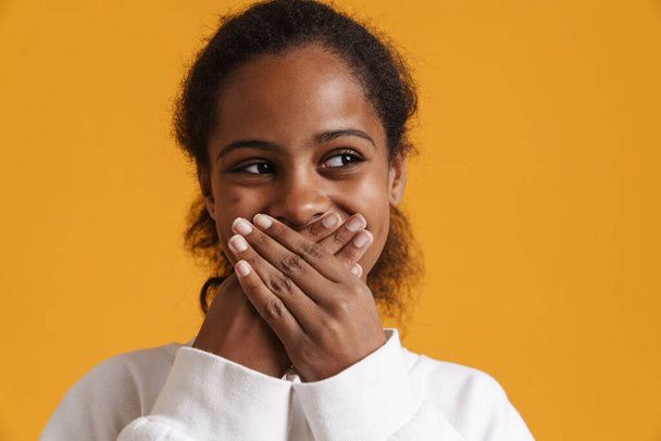 Brunette black girl wearing long-sleeve covering her mouth isolated over yellow background - Foto, Imagem