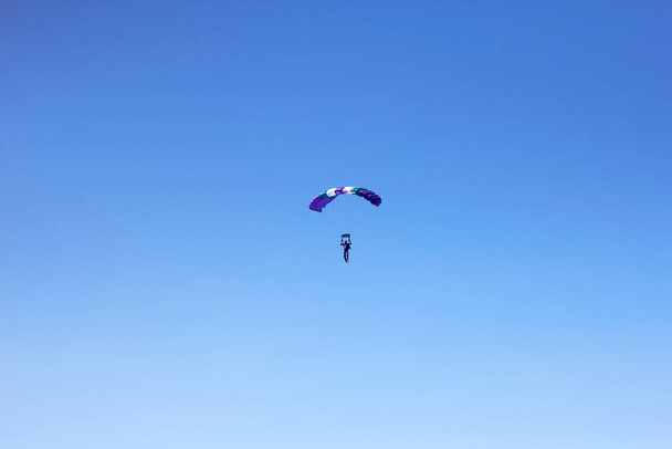 Kokeneen laskuvarjohyppääjän lento, jolla on ammattimainen laskuvarjo sinisellä taivaalla, suunta ja lasku tarkkuudella - Valokuva, kuva