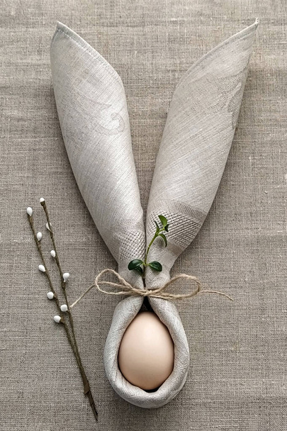 Dekoracyjne uszy króliczka z serwetki z jajkiem na naturalnym bawełnianym obrusie świętować Wielkanoc, DIY, płaskie układanki - Zdjęcie, obraz