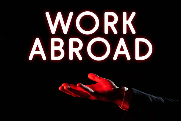 Text sign showing Work Abroad, Business overview Immersed in a foreign work environment Job Overseas Non Local Businessman In Suit Holding New Important Message In One Hand. - Photo, Image