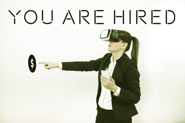 Handwriting text You Are Hired, Word Written on Recruitment being selected for a job the right candidate Woman Holding Mobile Phone, Wearing Vr Glasses And Pointing On New Idea. - Foto, Bild