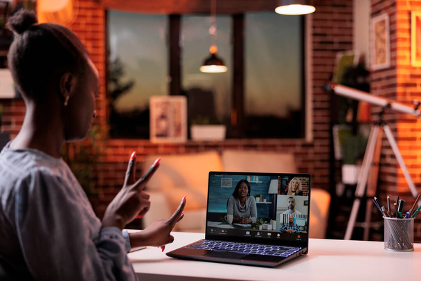 Online business meeting with coworkers, remote team brainstorming on teleconference. African american businesswoman chatting with colleagues on videconference using laptop, back view - Foto, Imagen