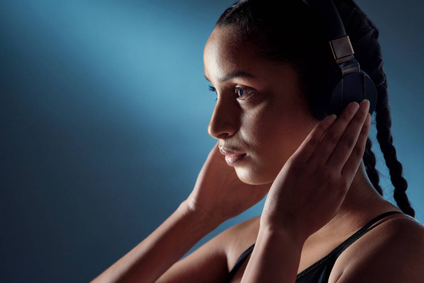 Change your mindset and everything else automatically does too. Studio shot of a sporty young woman listening to music against a blue background - Фото, изображение