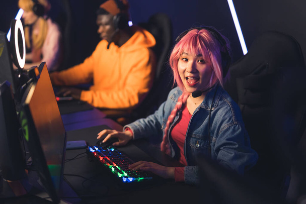 Young asian woman with pink hair wearing headset playing online game with friends looking excited into the camera. High quality photo - Photo, Image