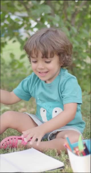 Happy Caucasian boy doing homework in park before back to school - Felvétel, videó