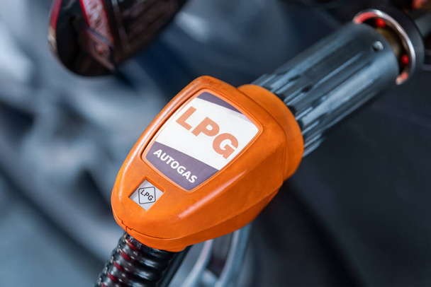 Close-up detail view of fuel autogas pump gun connected with noozle adapter to car tank to refill at car gas filling station. Refueling vehicle with liquefied lpg or lng product. Safety technology. - Fotoğraf, Görsel