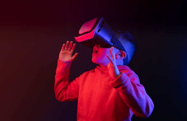 little boy wearing virtual reality glasses and looking surprised up in a futuristic environment. High quality photo - Fotó, kép