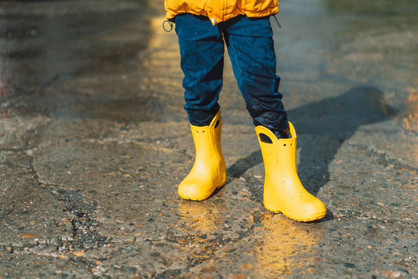 Boy in yellow rubber boots and wet jeans. - Zdjęcie, obraz