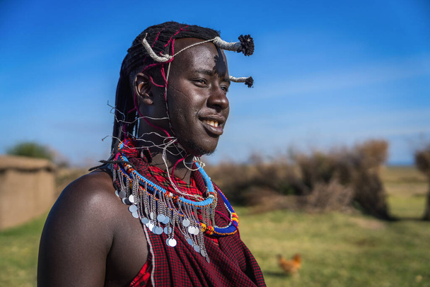 Portrait of Maasai mara man with traditional colorful necklace and clothing at Maasai Mara tribe village, Safari travel destination near Maasai Mara National Reserve, Kenya - Valokuva, kuva