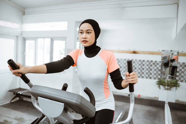 muslim women at the gym doing cardio exercises on static elliptical cycle machine - Photo, Image
