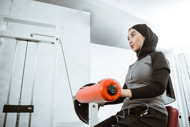 muslim asian woman working on her lower body using leg machine at the gym - Fotó, kép