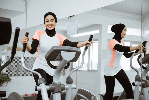 smiling beautiful women at the gym doing exercises on static elliptical cycle machine - Foto, Imagem