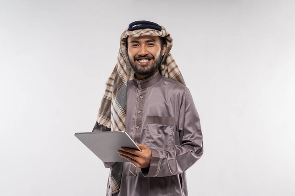 portrait of asian male with turban using a tablet against a plain white background - 写真・画像