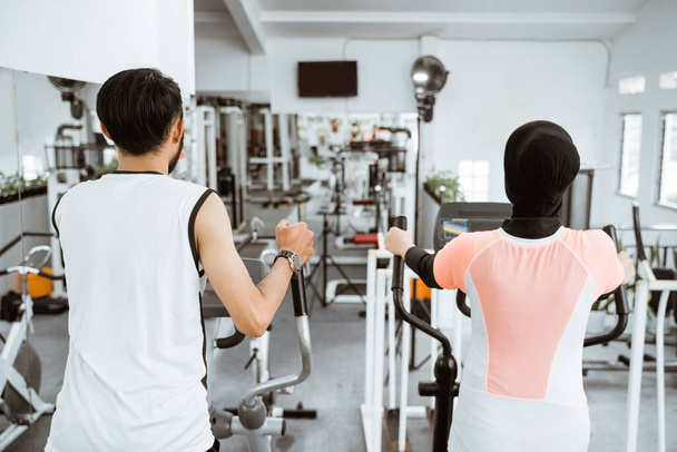 muslim couple using elliptical cycle machine for exercising together at the gym - Photo, Image