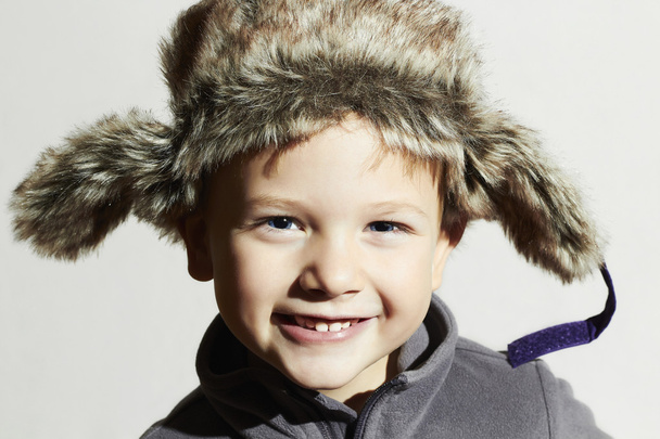 lächelndes Kind in Pelzmütze.kids lässigen Winter style.fashion kleine lustige boy.children emotion.hat Ohrenklappen - Foto, Bild