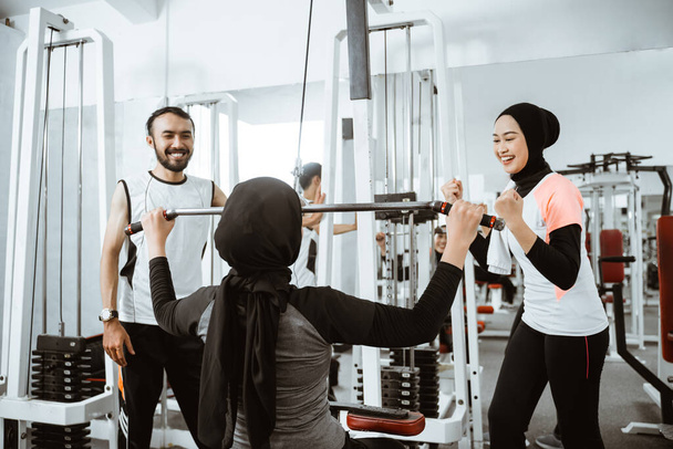 muslim asian woman exercising and getting supported by her trainer and friend during last repetition - Фото, зображення