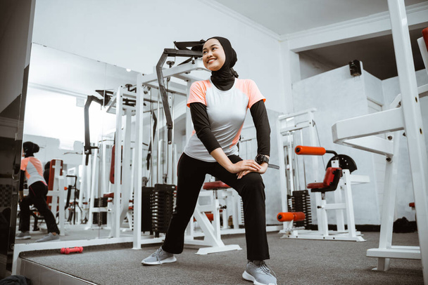 Attractive sports muslim girl smiles and stretching her body in the gym, lifestyle, healthy lifestyle. - Foto, Imagen