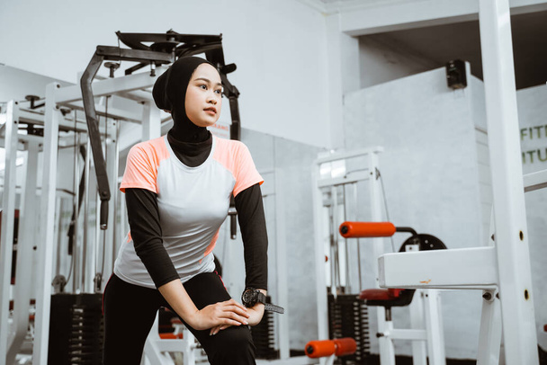 Приваблива спортивна мусульманська дівчина посміхається і розтягує тіло в спортзалі, стиль життя, здоровий спосіб життя
. - Фото, зображення