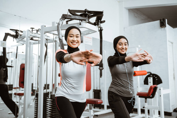 two beautiful muslim woman stretching and exercising at the gym together - Fotoğraf, Görsel