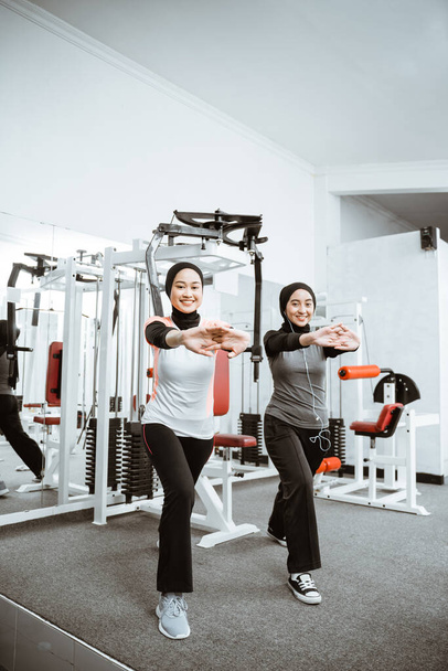 two beautiful muslim woman stretching and exercising at the gym together - Фото, зображення