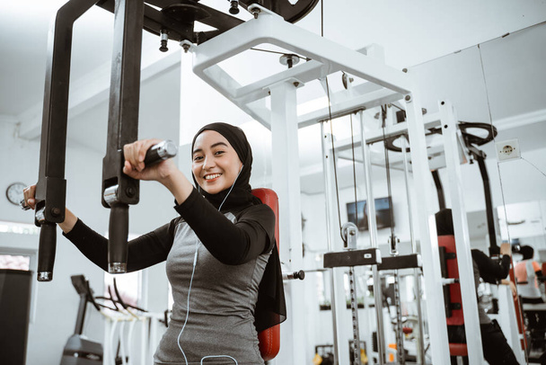 muslim asian woman using chest press machine during fitness at the gym - Φωτογραφία, εικόνα
