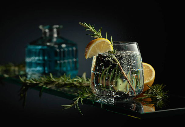 Gin tonic cocktail met citroen en rozemarijn. Koolzuurhoudende drank met belletjes. - Foto, afbeelding
