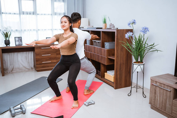 portrait of young asian couple workout together at home stretching their body - Fotoğraf, Görsel