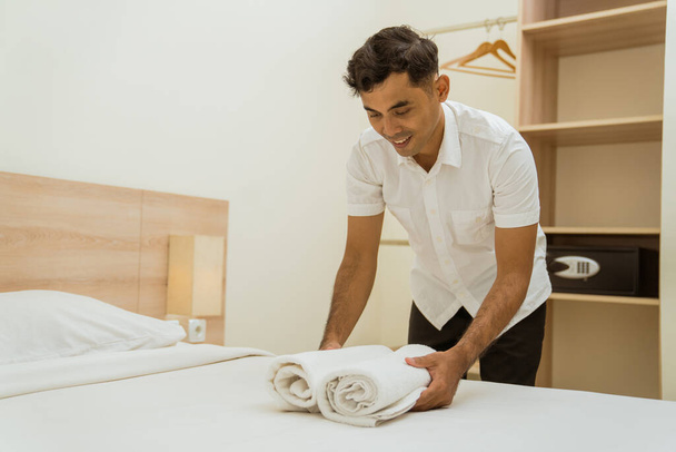 Young asian cleaning boy putting towel on hotel room bed - Φωτογραφία, εικόνα